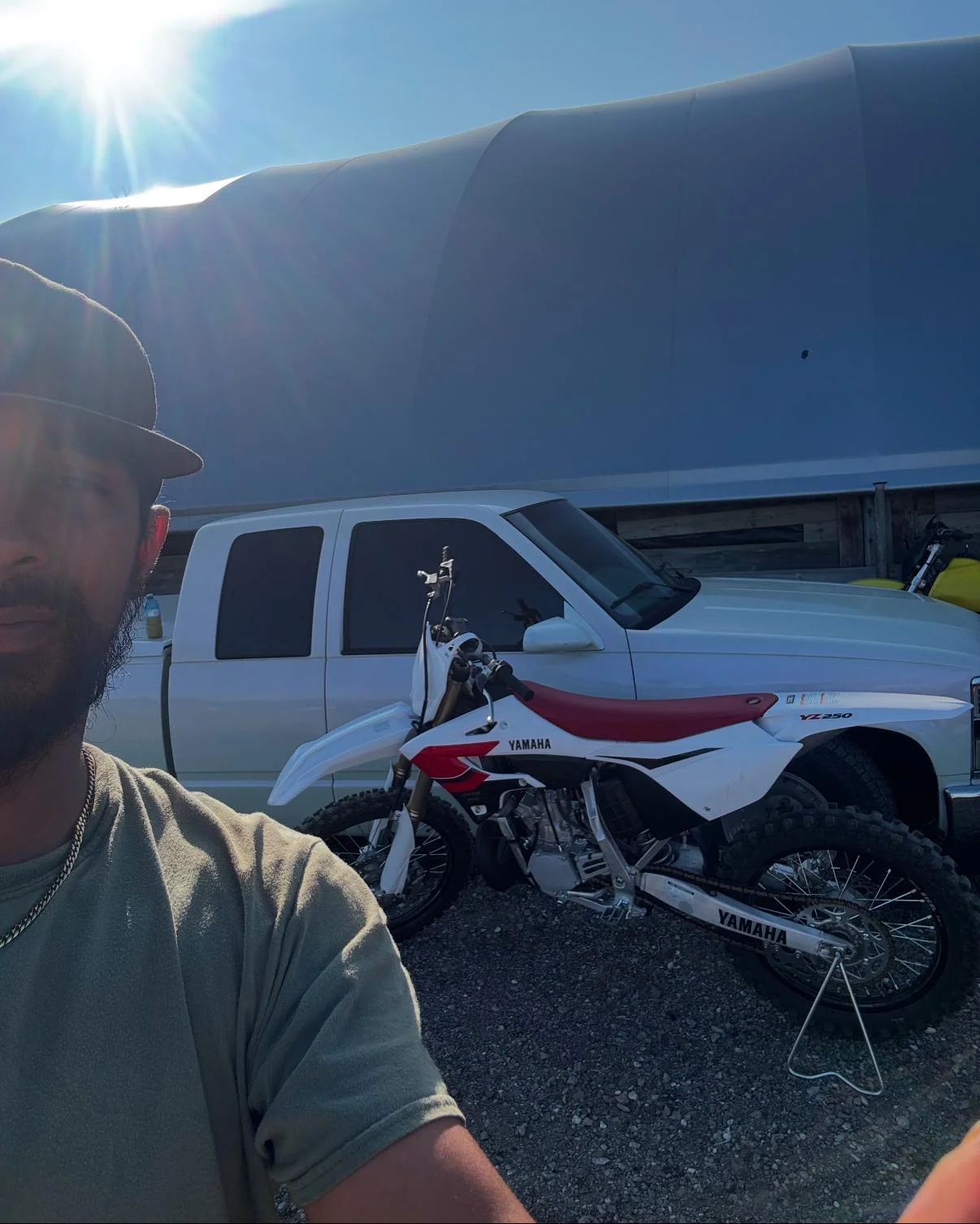Rider selfie beside a dirt bike and pickup truck