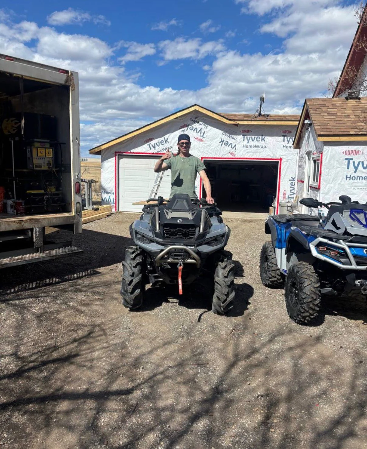 Customer with two ATVs beside a home under construction