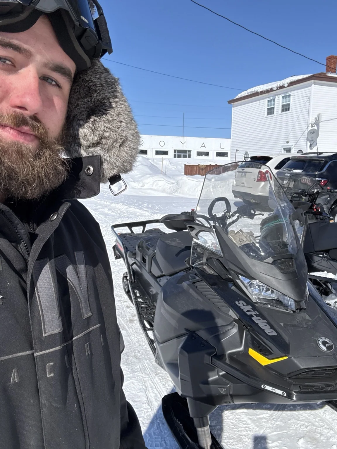 Rider selfie beside a snowmobile in winter