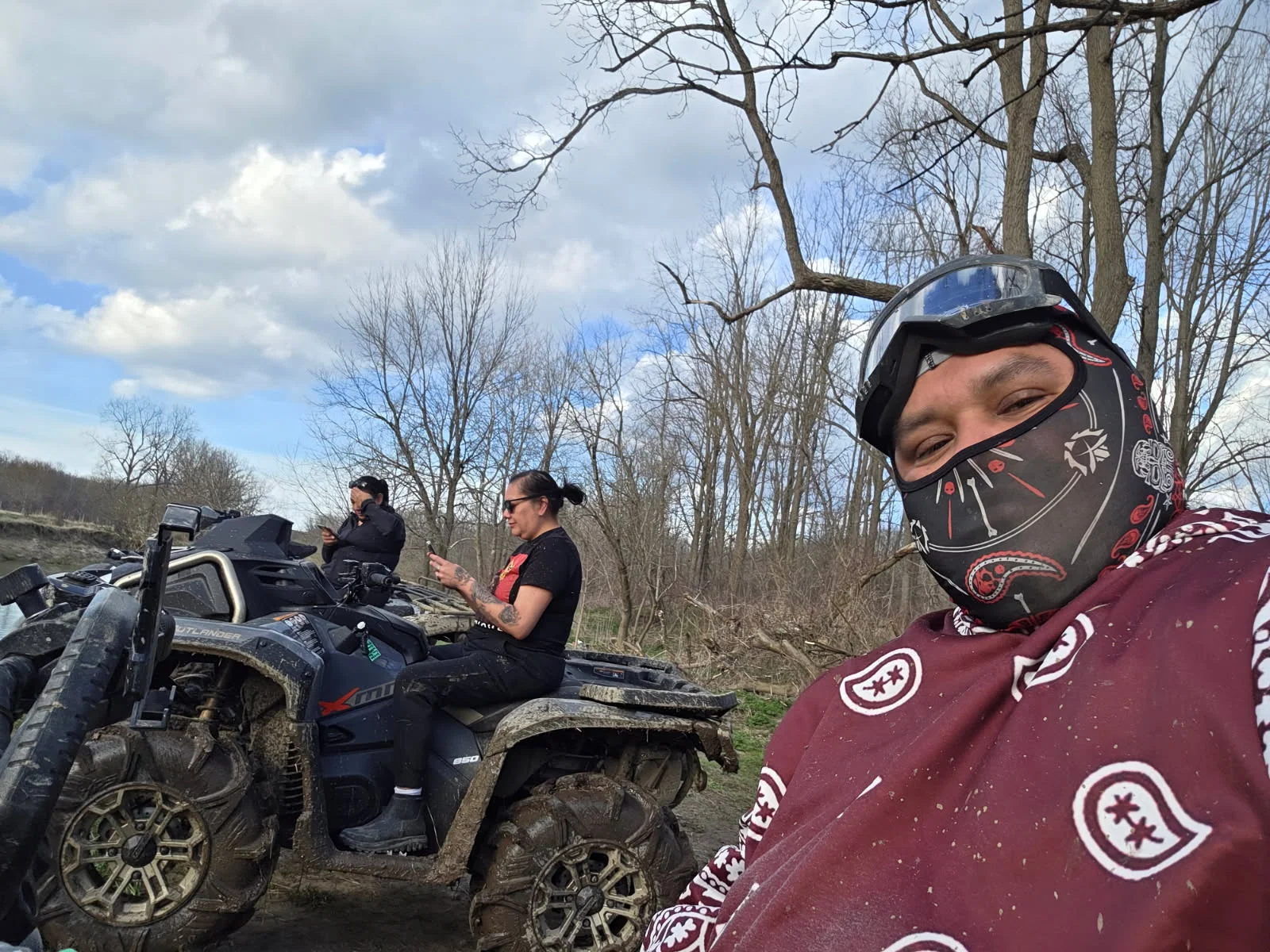 Riders taking a break with ATVs on a wooded trail
