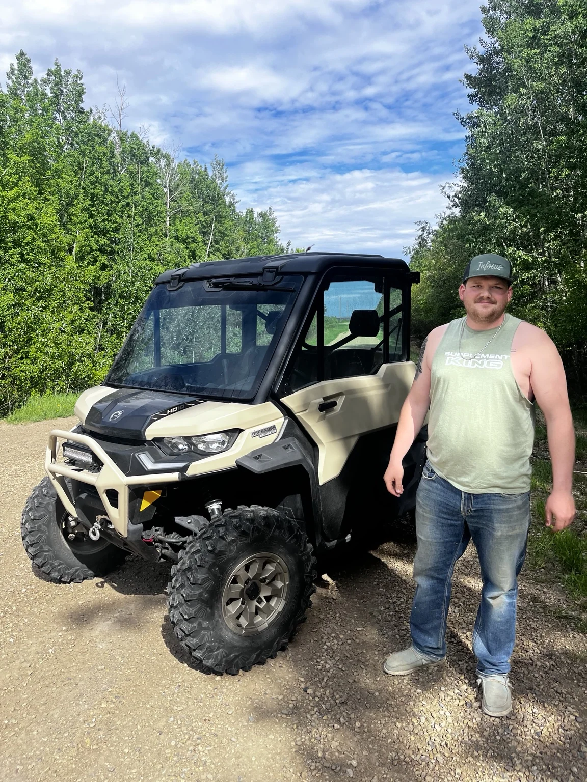 Customer beside a side-by-side on a wooded trail