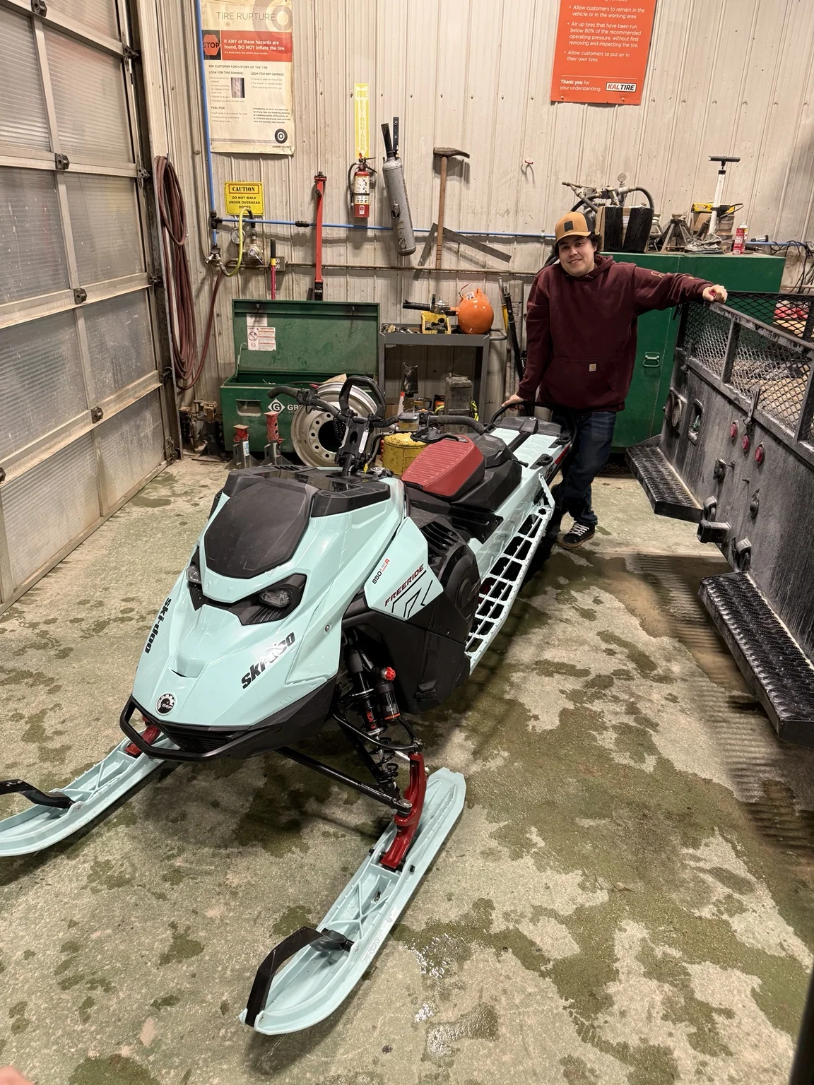 Customer beside a snowmobile indoors